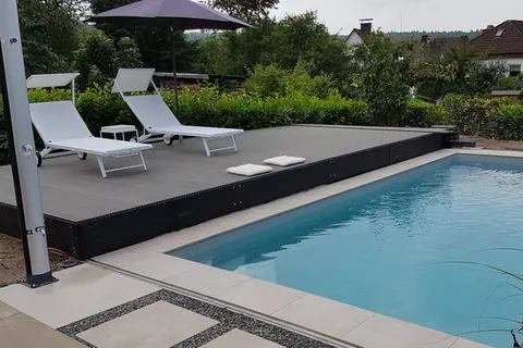 Einteiliges Pooldeck aus dunklem WPC in Parkposition neben dem offenen Pool